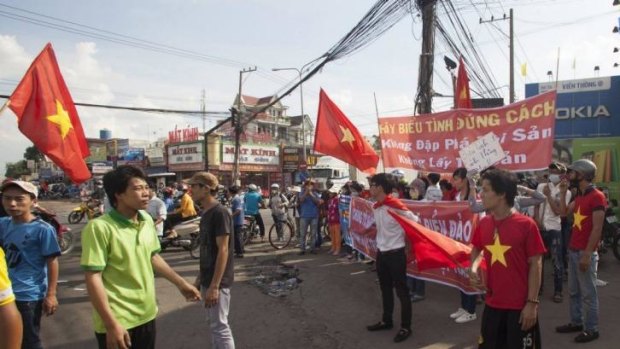 Workers wave Vietnamese flags at a demonstration in an industrial zone in Vietnam over the placement of China's rig.