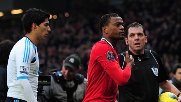 Patrice Evra of Manchester United celebrates victory as he walks off with Luis Suarez of Liverpool.