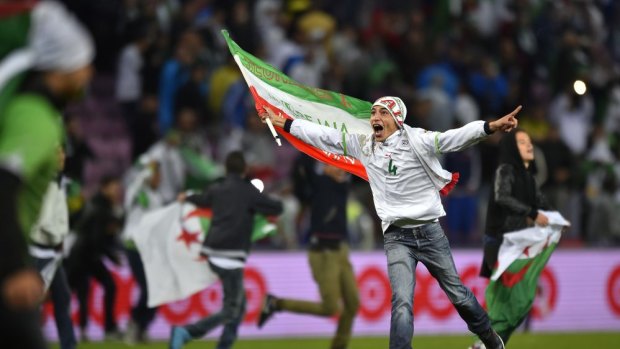 An Algeria supporter invades the field with others as they celebrate Algeria winning the friendly football match between Algeria and Romania.