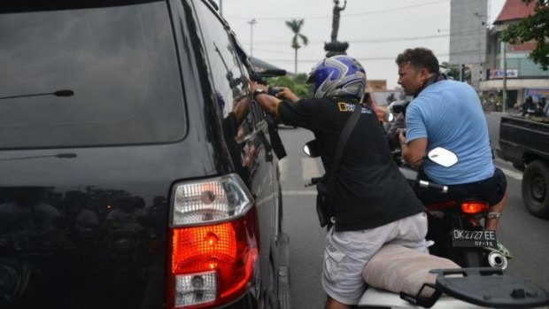 Photographers and videographers try to get images through a car window of Australian drug trafficker Schapelle Corby.