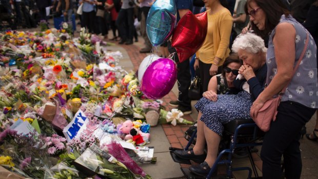 Women cry after placing flowers in a square in central Manchester, Britain, Wednesday, May 24, 2017, after the suicide attack at an Ariana Grande concert.