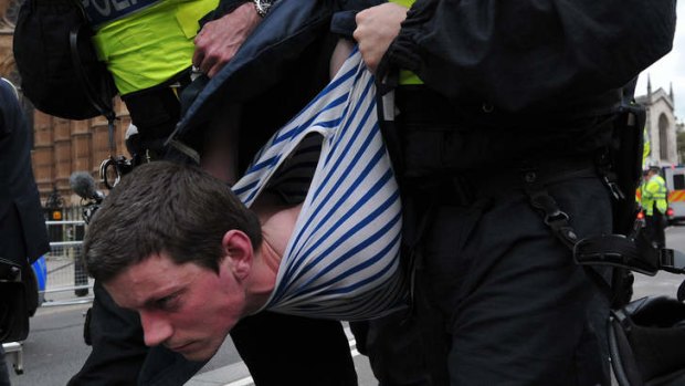 A United Against Fascism protester is removed by the police during a demonstration against the British National Party (BNP) in central London on June 1, 2013.