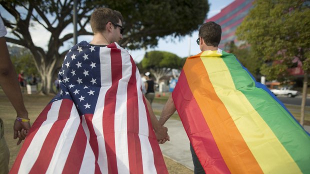 Robert Oliver and Mark Heller (R) hold hands, draped in flags, as they celebrate the Supreme Court ruling on same-sex marriage on June 26, 2015 in West Hollywood, California. 