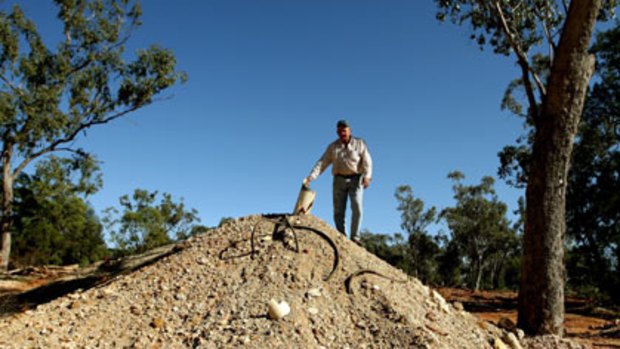 ‘‘We are bathing in their rubbish’’ ... Kevin Parkins shows off the mining detritus he wants cleaned up on his property near Lightning Ridge.