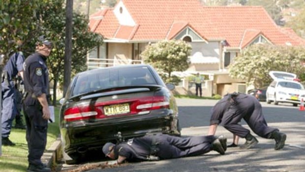Looking for answers...police search for evidence under a car near the scene of the fatal shooting in Cremorne.