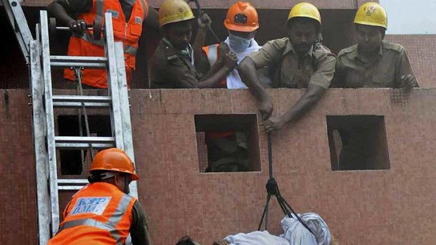 Rescue workers use ropes to evacuate a woman from the AMRI hospital in Kolkata.