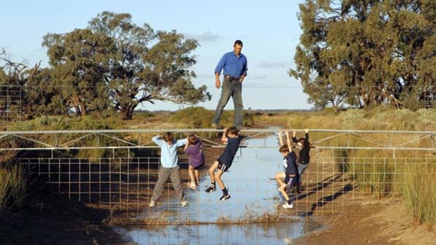 High and dry ... Riverina rice farmer, Jeremy Morton, with some local children. Mr Morton wants to sell his water entitlements,  and close this irrigation channel so he can give up farming.