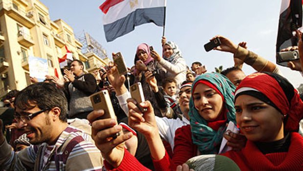 Young Egyptian men and women use their mobile phones to record the celebrations in Egypt's Tahrir Square at the overthrow of President Hosni Mubarak.