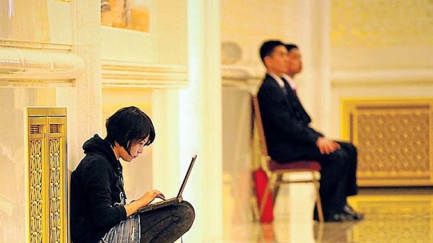 A reporter outside the Chinese Political Consultative Congress crouches with a computer to meet a deadline.
