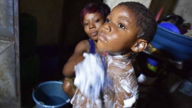 A woman washes her child with salted water in a suburb of Abidjan, relying on a rumour that was spread in the area claiming that salted water helps to fight against the Ebola virus.