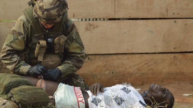 A French soldier gives first aid to an injured looter in Bangui.