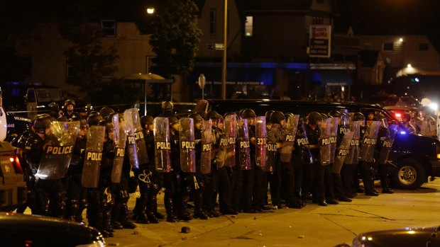 Police are pelted with rocks and shots rang out in Milwaukee, Sunday, Aug. 14, 2016. Police said one person was shot at a Milwaukee protest on Sunday and officers used an armored vehicle to retrieve the injured victim and take the person to a hospital, as tense skirmishes erupted for a second night following the police shooting of a black man. (AP Photo/Jeffrey Phelps)
