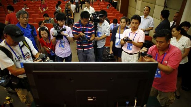 First glimpse: Journalists take pictures and videos of a screen displaying a court's microblog page showing a video of Gu Kailai.