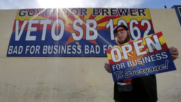 A protester against Senate Bill 1062 shows a sign that reads "Open For Business To Everyone" in Phoenix, Arizona.