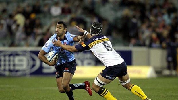 Tah tackle . . . Kurtley Beale of the Waratahs fends off a challenge in the Super Rugby game against the Brumbies.