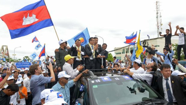 Cambodian opposition leader of the Cambodia National Rescue Party Sam Rainsy (centre right) and Kem Sokha (centre left) Vice president of the CNRP greet their supporters along a street in Phnom Penh.