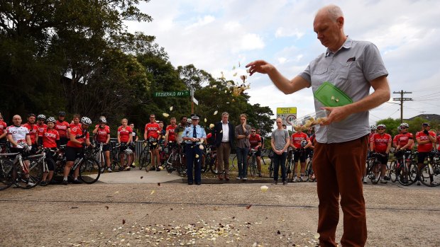 Andrew Zoerner, the father of Nicholas Ruygrok's fiancee, drops rose petals at the site of the fatal crash as members of the Dulwich Hill Bicycle Club look on.