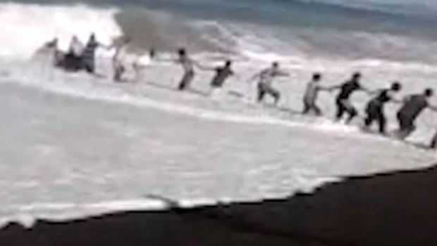 Beachgoers form a human chain to try and rescue a boy.