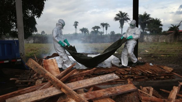 A burial team from the Liberian Ministry of Health unloads the bodies of Ebola victims onto a funeral pyre at a crematorium.