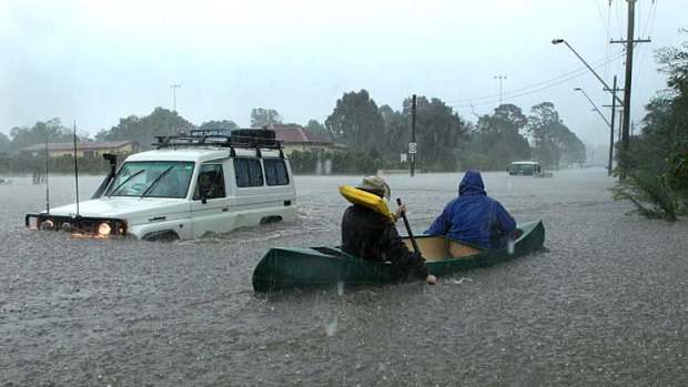 The day roads turned into rivers ... Sam Harris uses a canoe to make his way down Bong Bong Road at Dapto.