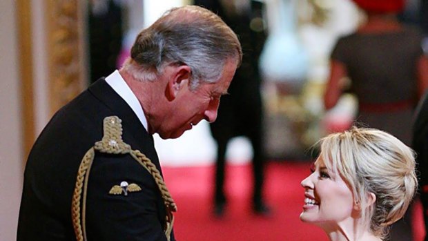 Prince Charles confers an OBE on Kylie Minogue at Buckingham Palace yesterday. Her sister, Dannii, mother Carol and father Ron attended the ceremony.