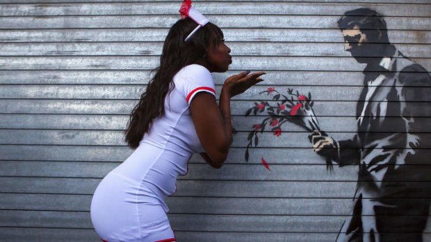 A dancer poses with a new installation of art by British graffiti artist Banksy painted on the front door of the Hustler Club in New York.