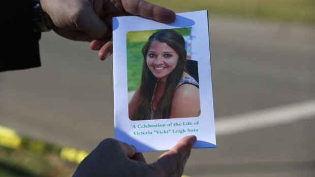 A mourner displays a program for the funeral of slain teacher Victoria Soto.
