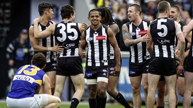All smiles: Collingwood players congratulate each other on their hard-fought victory as a dejected Luke Shuey looks on.