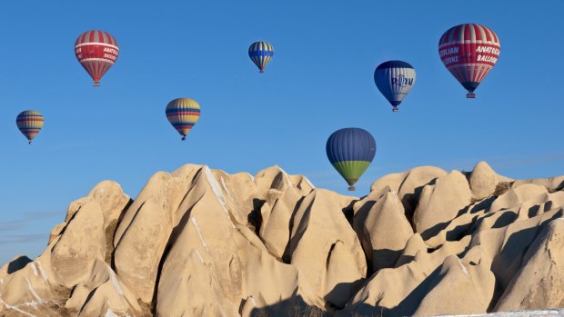Hot-air balloons over snow-tipped rock formations in Cappadocia in Turkey.