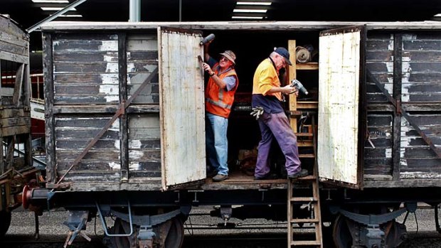 Trains kept a-rollin' ... Alfred Ward and Allan Leaver scrape paint off an old Arnott's Biscuits carriage at Trainworks.