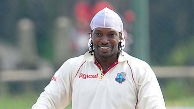 West Indies batsman Chris Gayle raises his bat and helmet in celebration after reaching his second triple hundred in Test cricket.