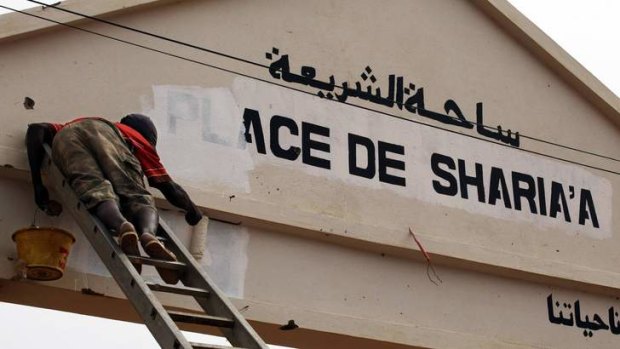 Islamic law rejected ... a city worker paints over a sign reading "Sharia Square" in Gao on Sunday. Radical Islamists painted many signs proclaiming sharia law during their nine-month occupation of the northern Malian city.