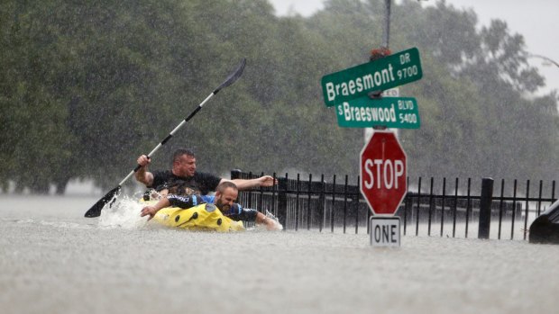 Two men try to beat the current pushing them down a road in Houston during Hurricane Harvey's deluge in August.