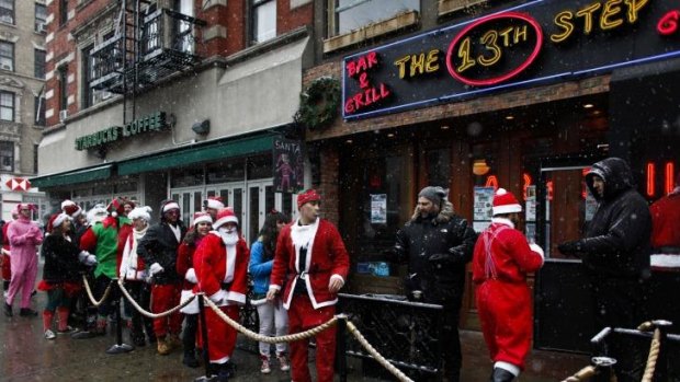 Dress code: Bouncers vet the Santa suits at a local pub during SantaCon in New York.