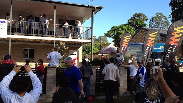 People gather to watch the official handover of the house at Slacks Creek.