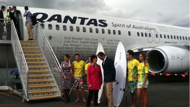 Qantas CEO Lyell Strambi and Queensland Tourism Minister Jann Stuckey speak in front of the "Surf Board welcoming committee" as passengers disembark from the Sydney to Gold Coast flight.
