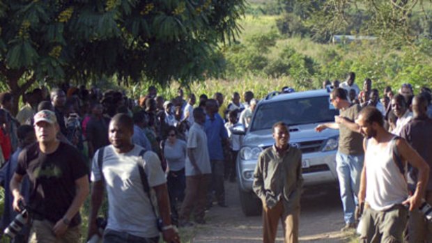 Villagers and reporters crowd around a convoy of cars transporting Madonna in Lilongwe, Malawi, on Sunday.