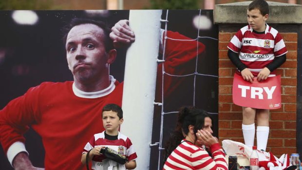 Competing codes: Supporters of Wigan Warriors alongside a photograph of Manchester United legend Nobby Stiles ahead of the Super League grand final last year.