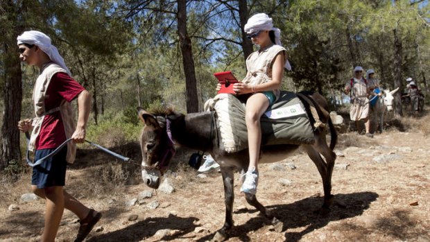 American tourist Ella uses an iPad while riding a wi-fi-outfitted donkey lead by her brother Aaron, in Kfar Kedem, a biblical reenactment park in the village of Hoshaya in the Galilee, northern Israel.