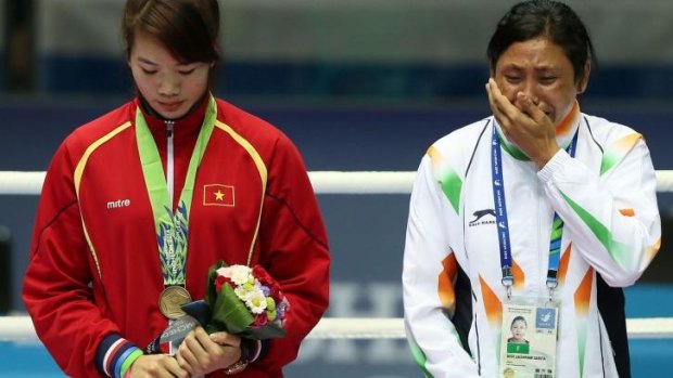 Sarita Devi is in tears as she stands on the podium.