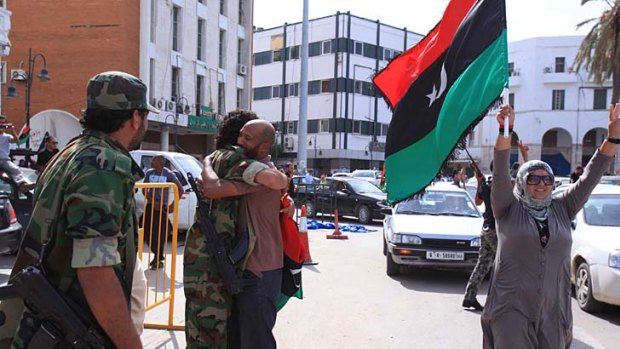 Libyan National Transitional Council fighters are congratulated during celebrations in the streets of Tripoli  following news of Muammar Gaddafi's death.