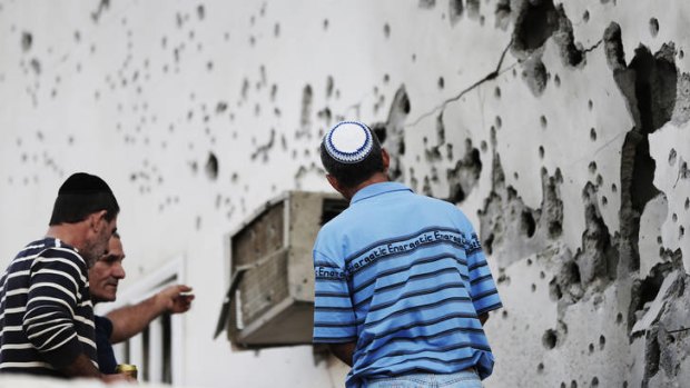 Residents in Okafim, southern Israel, inspect the damage from a rocket fired from Gaza.