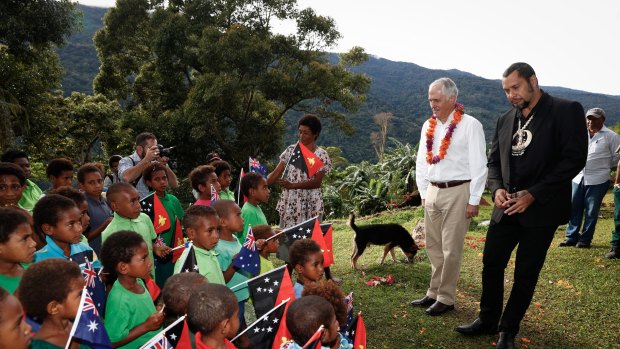 Children sing the national anthem of Papua New Guinea to Prime Minister Malcolm Turnbull, who is accompanied by the Governor of Oro Province, Gary Juffa (on right), during his visit to the Isurava Memorial to lay a wreath at the Kokoda Track.
