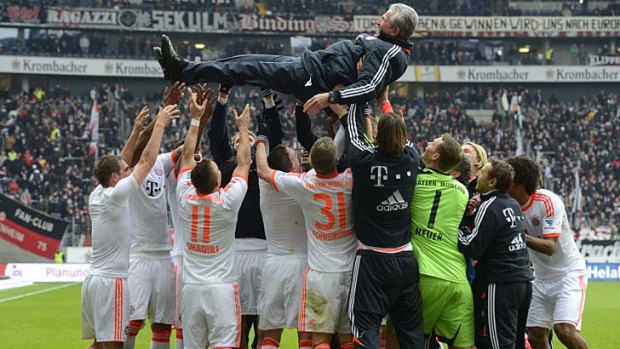 Bayern Munich players lift their head coach Jupp Heynckes in the air after winning the game against Eintracht Frankfurt.