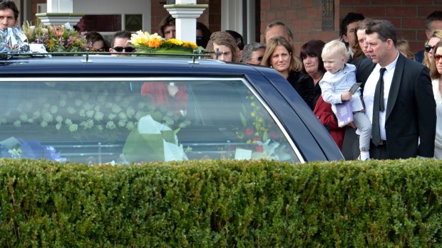 Brett Ratten (holding a child) at the funeral of his son Cooper Ratten. 