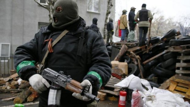 An armed man stands next to a barricade in front of the police headquarters in Slaviansk. 