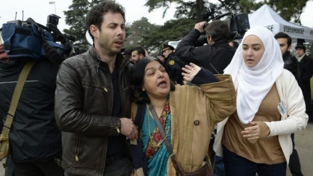 Ms Khan, escorted away by friends after trying to speak with members of the Syrian regime in Geneva.