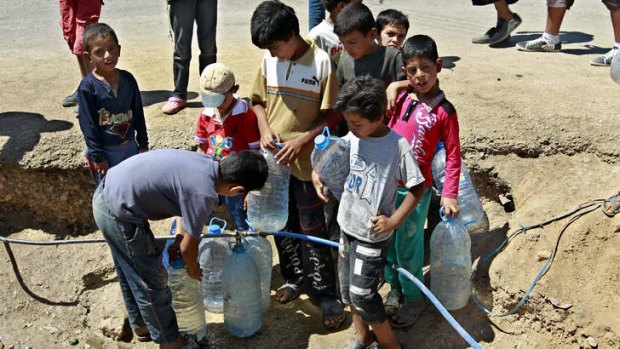 Homeless: Refugees fill up water bottles at a temporary camp set up in the eastern Lebanese town of Faour near the border with Syria.