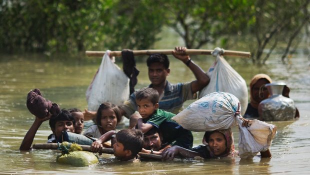 A Rohingya family fleeing Myanmar reaches the Bangladesh border after crossing a creek.