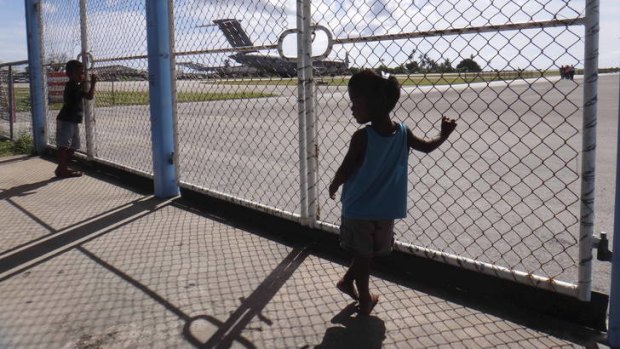 Nauruans watch a Royal Australian Air Force C-17 Globemaster III. The plane's arrival this week was a first step in creating a new immigration detention centre there.     20120824 airport7.jpg
